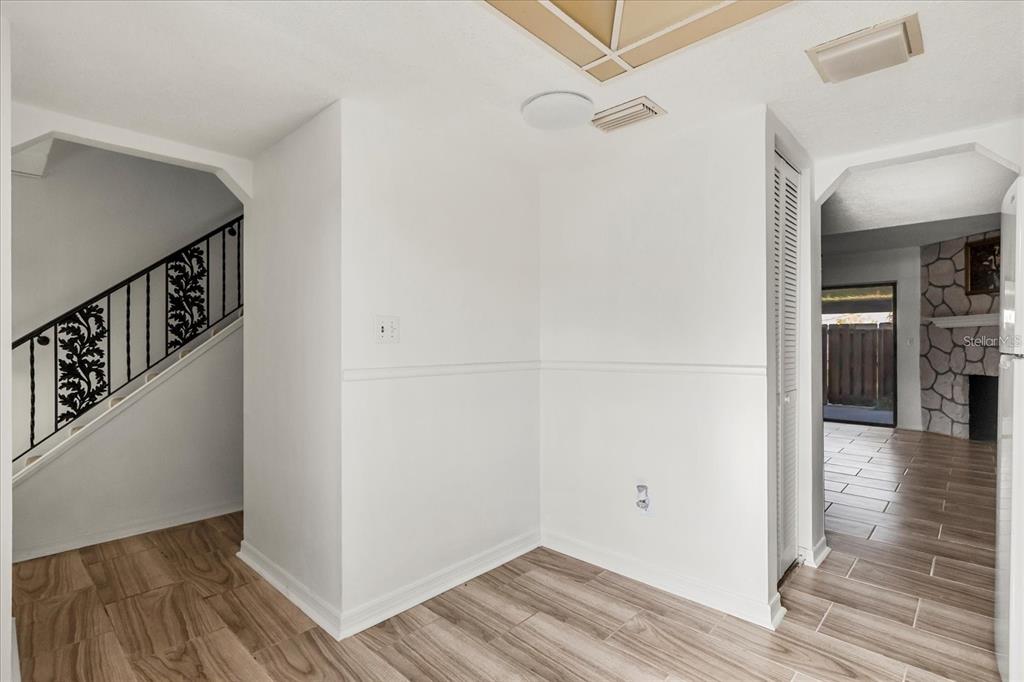 A room with wood-look tile flooring, white walls, a staircase, and a view into another room — 2250 S PALMETTO AVENUE UNIT i-11, DAYTONA BEACH, FL