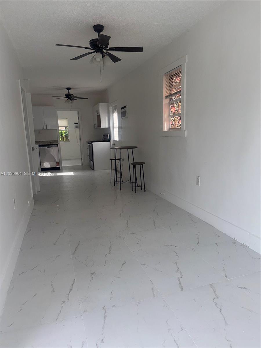 A narrow kitchen and dining area features white marble-patterned tile floors and white cabinetry — 713 NW 4th St, Hallandale Beach FL 33009, HALLANDALE BEACH, FL