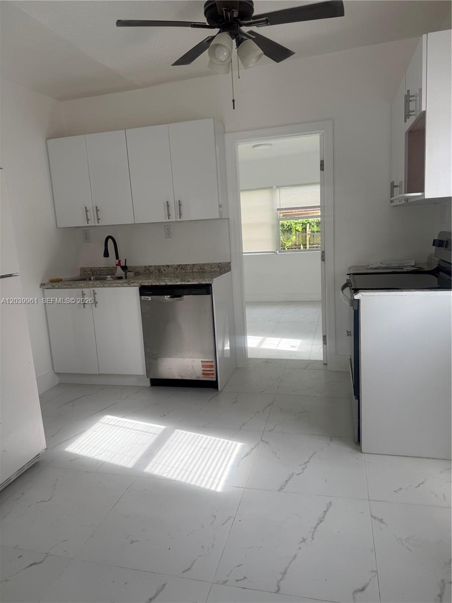A kitchen features white cabinets, stainless steel appliances, and light-colored marble-patterned tile flooring — 713 NW 4th St, Hallandale Beach FL 33009, HALLANDALE BEACH, FL