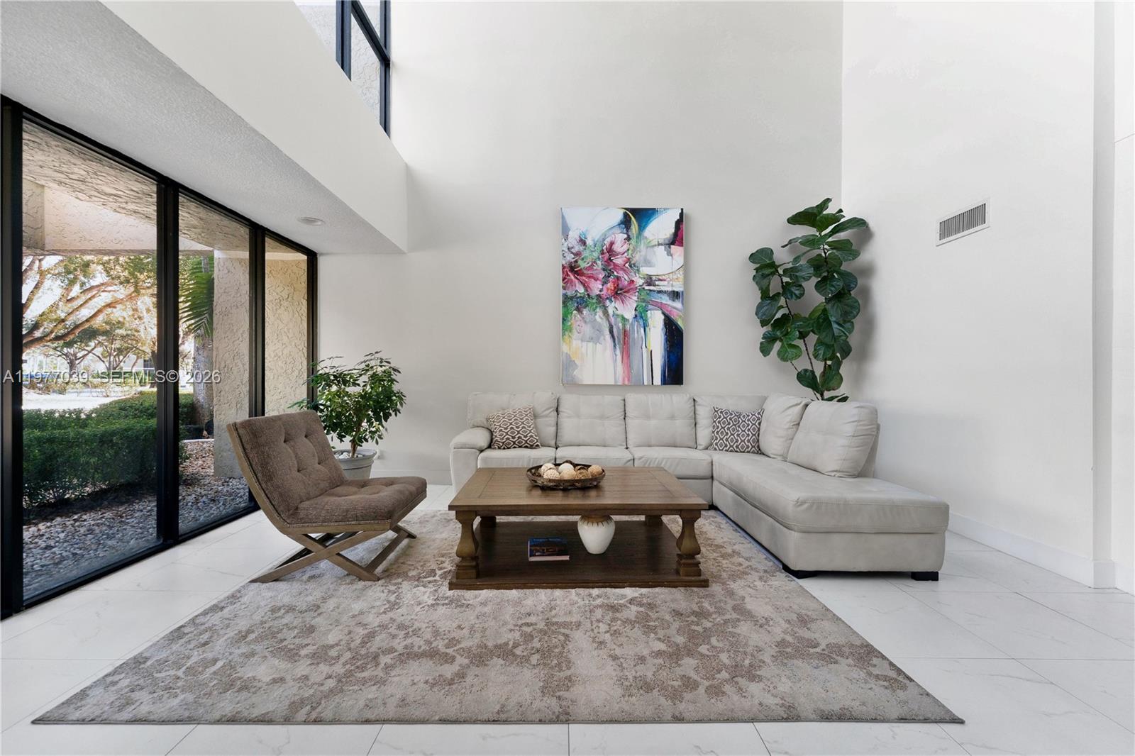 A living room features a sectional sofa, a coffee table, and a large abstract painting — 16200 Golf Club Rd # 102, Weston FL 33326, WESTON, FL