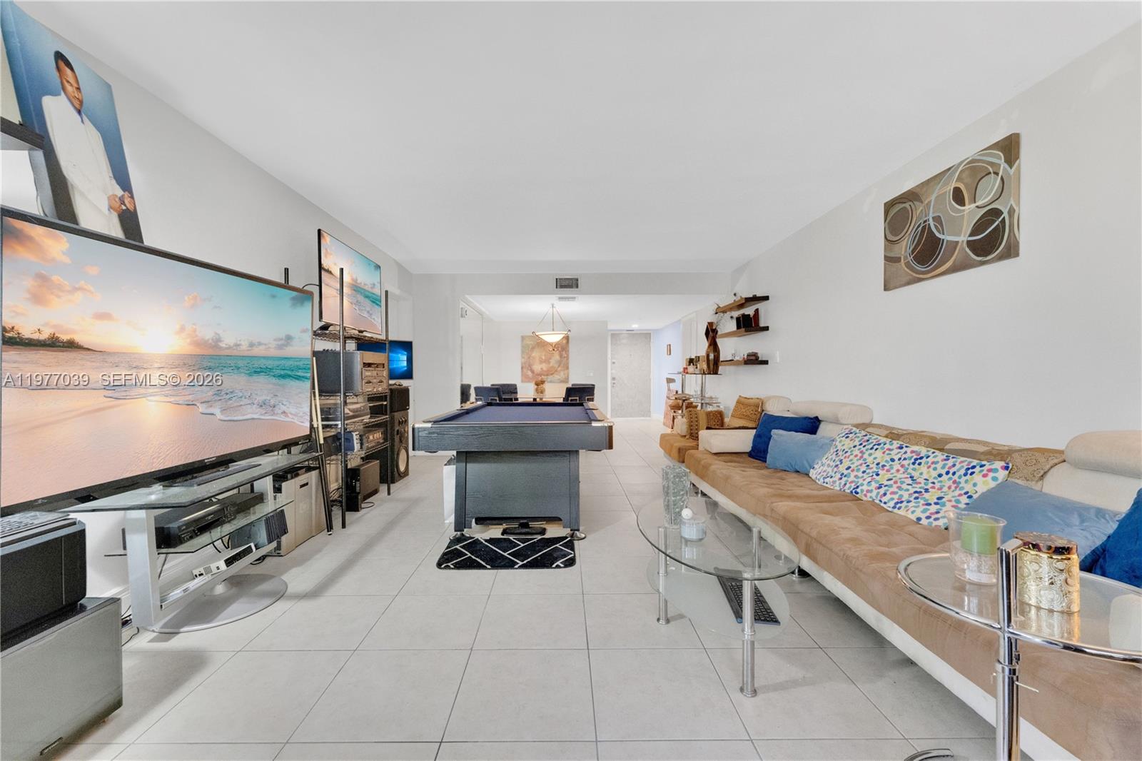 A living room features a pool table, a large television, and a long brown sofa — 16200 Golf Club Rd # 102, Weston FL 33326, WESTON, FL