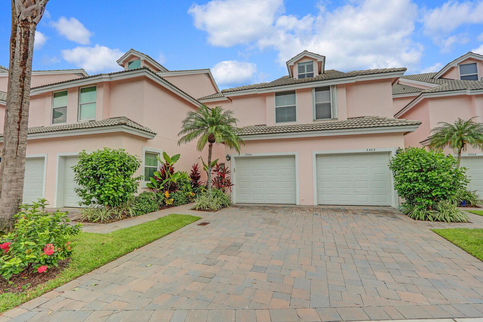 A row of pink two-story townhouses features white garage doors and a paved driveway — 3306 Fairway Drive N, Jupiter FL 33477, JUPITER, FL