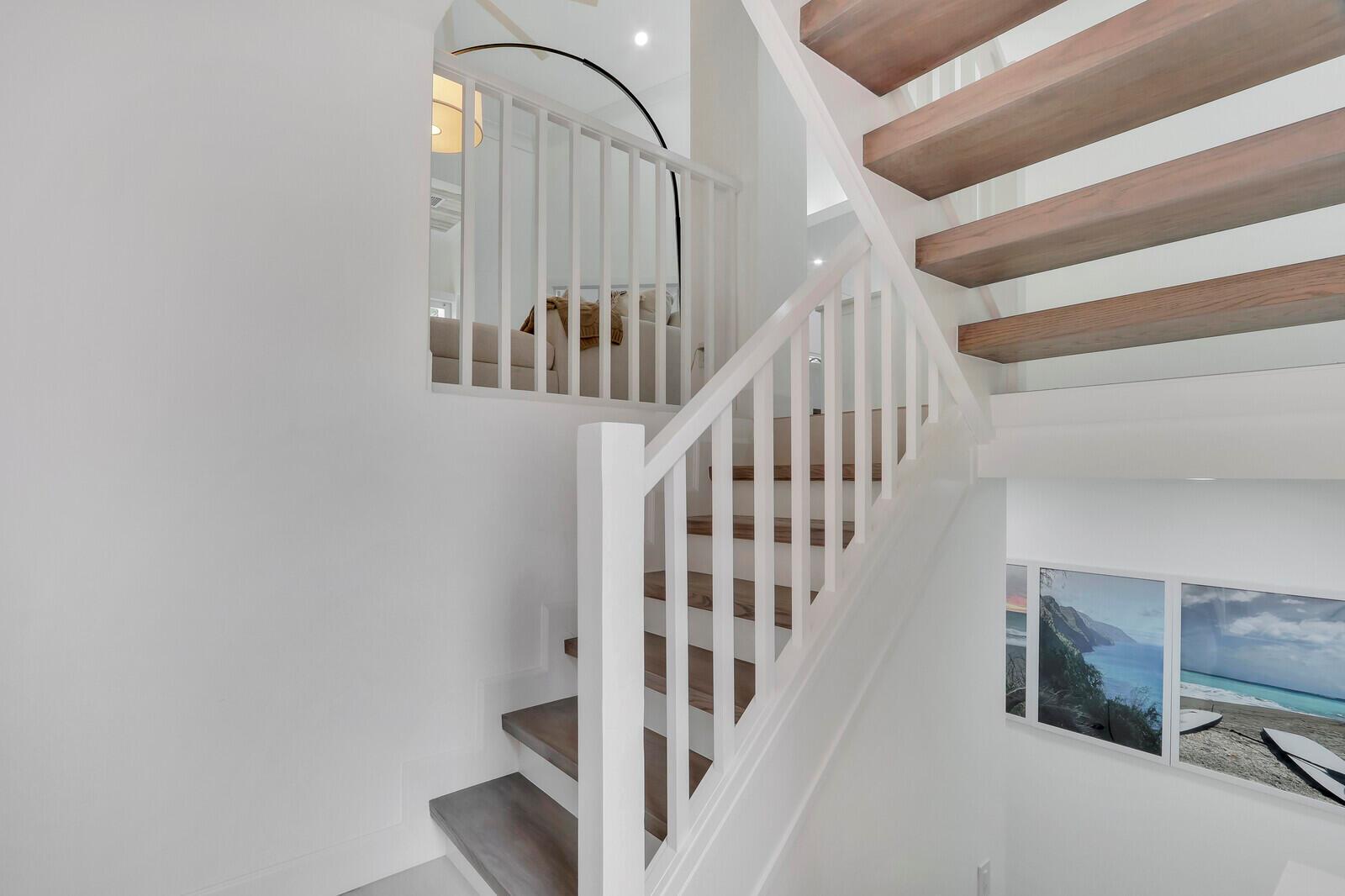 A staircase with wooden treads and white railings leads to an upper landing — 3306 Fairway Drive N, Jupiter FL 33477, JUPITER, FL