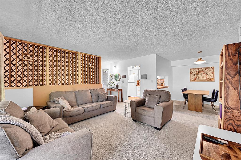 A living room features a wooden lattice room divider, beige carpet, and an adjacent dining area — 117 Gardens Drive # 204, Pompano Beach FL 33069, POMPANO BEACH, FL