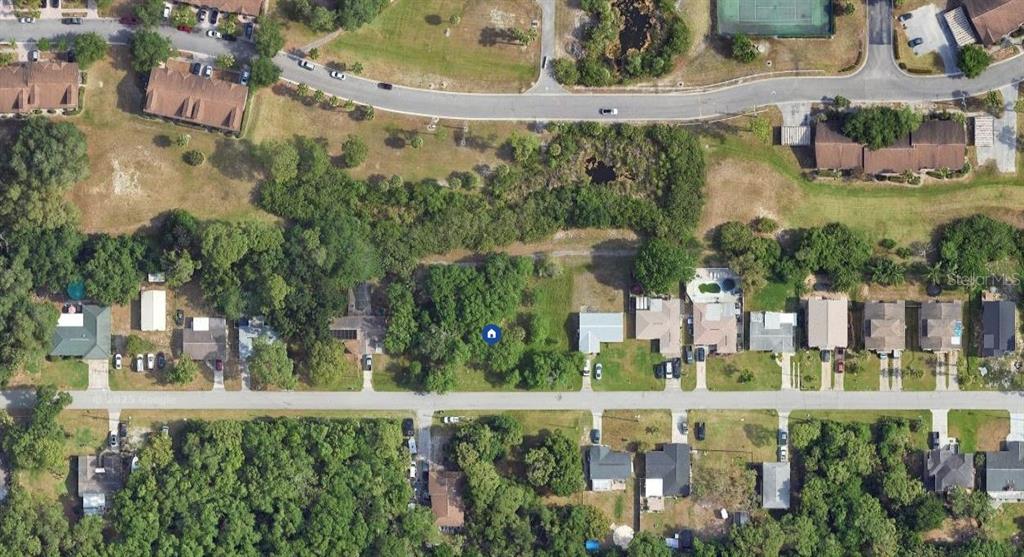 This aerial view shows a residential street with houses, wooded areas, and a nearby road — 8149 GULF WAY, HUDSON, FL