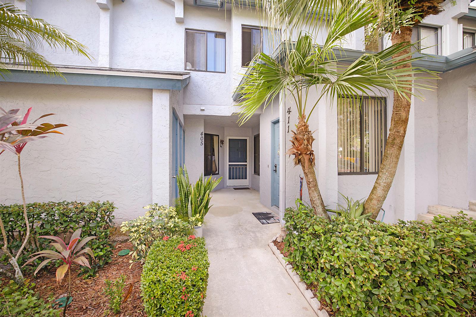 The exterior view shows a walkway leading to two residential unit entrances with tropical landscaping — 405 Harbour Pointe Way, FL 33413, FL
