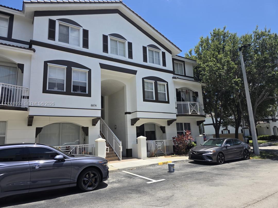 A three-story residential building with white stucco walls, dark trim, and a central staircase — 8874 W Flagler St # 101, Miami FL 33174, MIAMI, FL