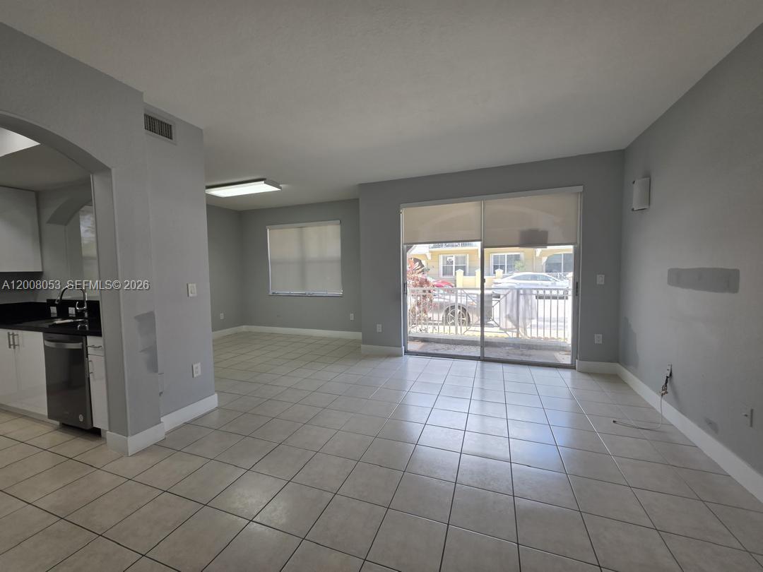 An open-concept living area features light gray walls, tile flooring, and a sliding glass door — 8874 W Flagler St # 101, Miami FL 33174, MIAMI, FL
