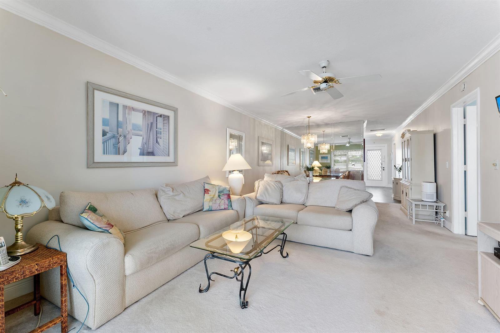 A living room features a beige sectional sofa, a glass coffee table, and mirrored walls — 2401 Del-aire Boulevard E # 201, Delray Beach FL 33445, DELRAY BEACH, FL