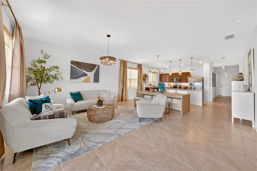 An open-concept living room and kitchen featuring tile floors, neutral furniture, and pendant lighting — 415 OVERPOOL AVENUE, DAVENPORT, FL