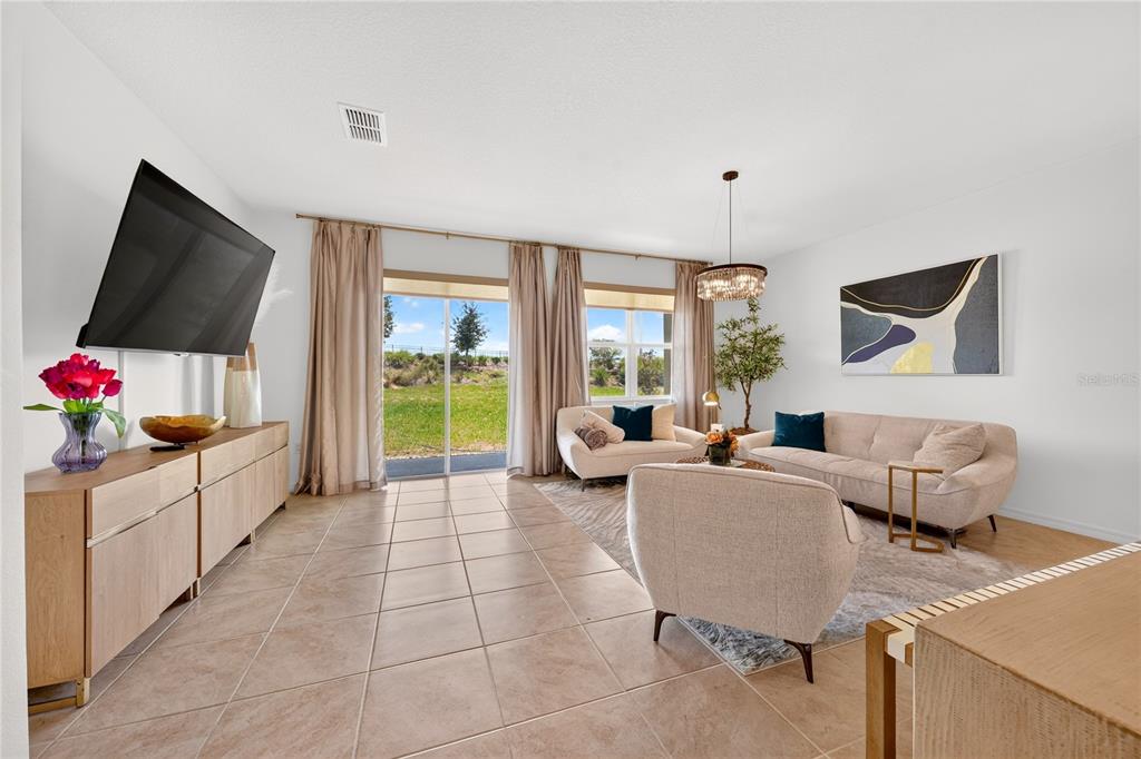 A living room features tile flooring, a television, a sofa, and sliding glass doors — 415 OVERPOOL AVENUE, DAVENPORT, FL