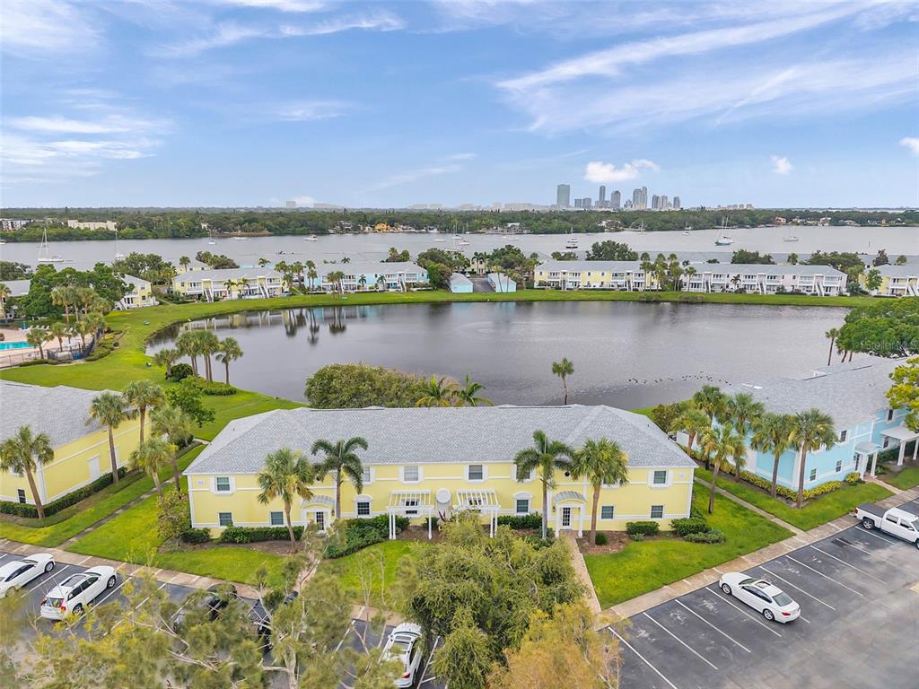 An aerial view shows a yellow multi-story apartment building beside a pond and parking lot — 121 SEAHORSE DRIVE SE UNIT A, ST PETERSBURG, FL
