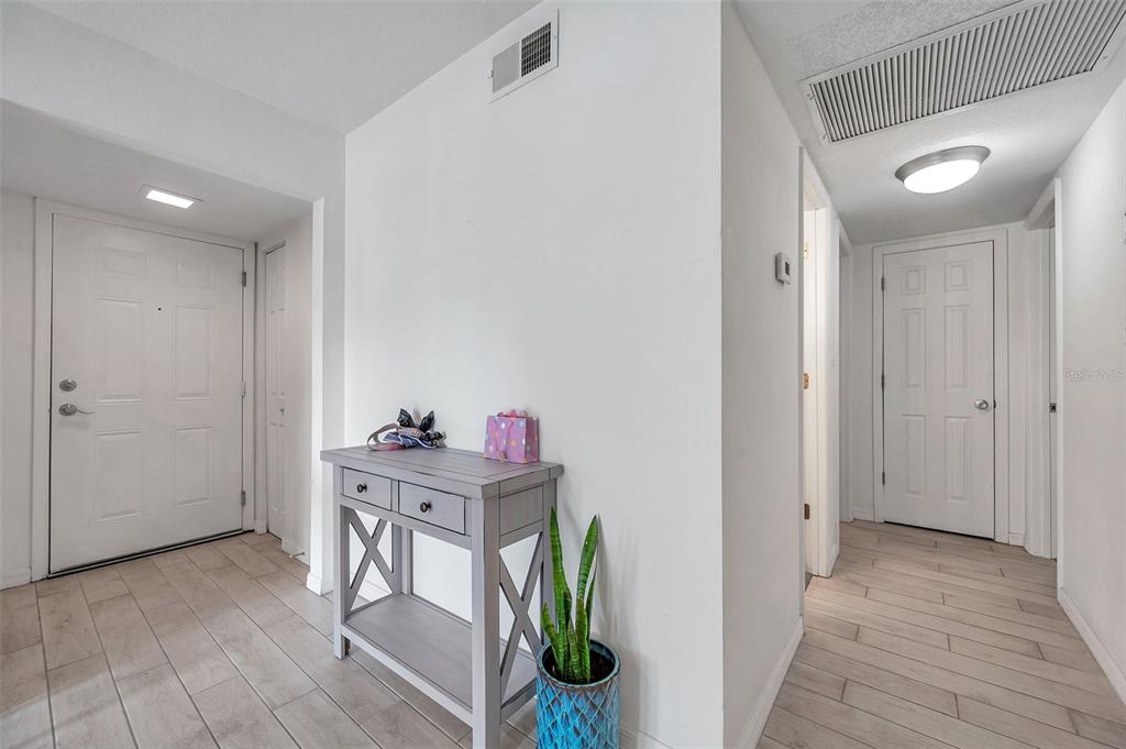 A bright entryway features light-colored tile flooring, a gray console table, and white interior doors — 121 SEAHORSE DRIVE SE UNIT A, ST PETERSBURG, FL
