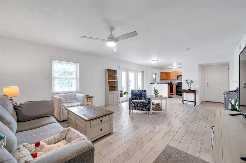 A living room with light tile flooring, a ceiling fan, and an open kitchen beyond — 121 SEAHORSE DRIVE SE UNIT A, ST PETERSBURG, FL