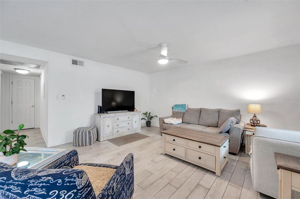 A living room features a gray sofa, a wooden coffee table, and light-colored tile flooring — 121 SEAHORSE DRIVE SE UNIT A, ST PETERSBURG, FL