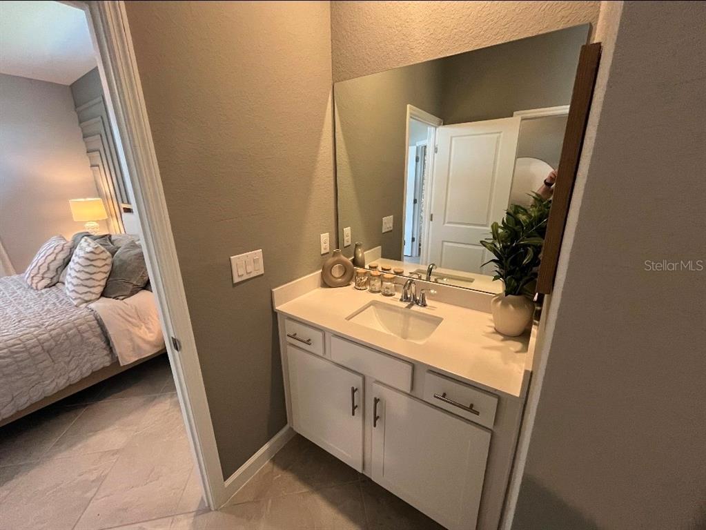 A bathroom vanity with a white cabinet, quartz countertop, and a large wall mirror — 8141 SHORE LAKE DRIVE, ENGLEWOOD, FL