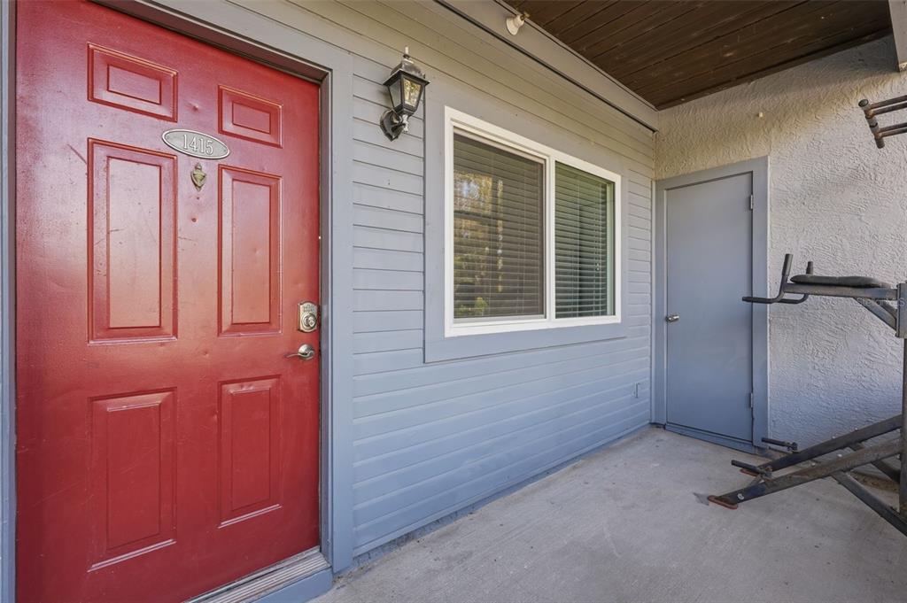 A red front door and a gray exterior wall with a window and storage closet — 10265 GANDY BOULEVARD N UNIT 1415, ST PETERSBURG, FL