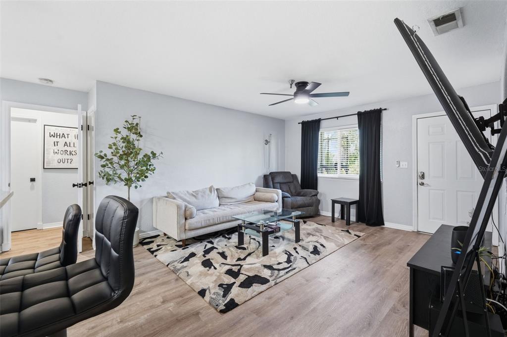 A living room features light wood-look flooring, a beige sofa, and a patterned area rug — 10265 GANDY BOULEVARD N UNIT 1415, ST PETERSBURG, FL