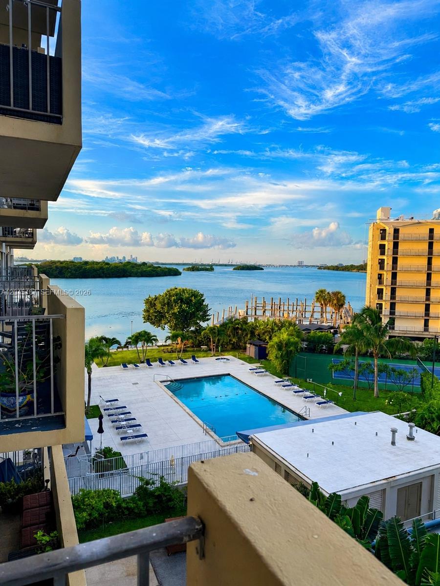 An elevated view shows a swimming pool, palm trees, and a bay with distant buildings — 880 NE 69th St # 5L, Miami FL 33138, MIAMI, FL