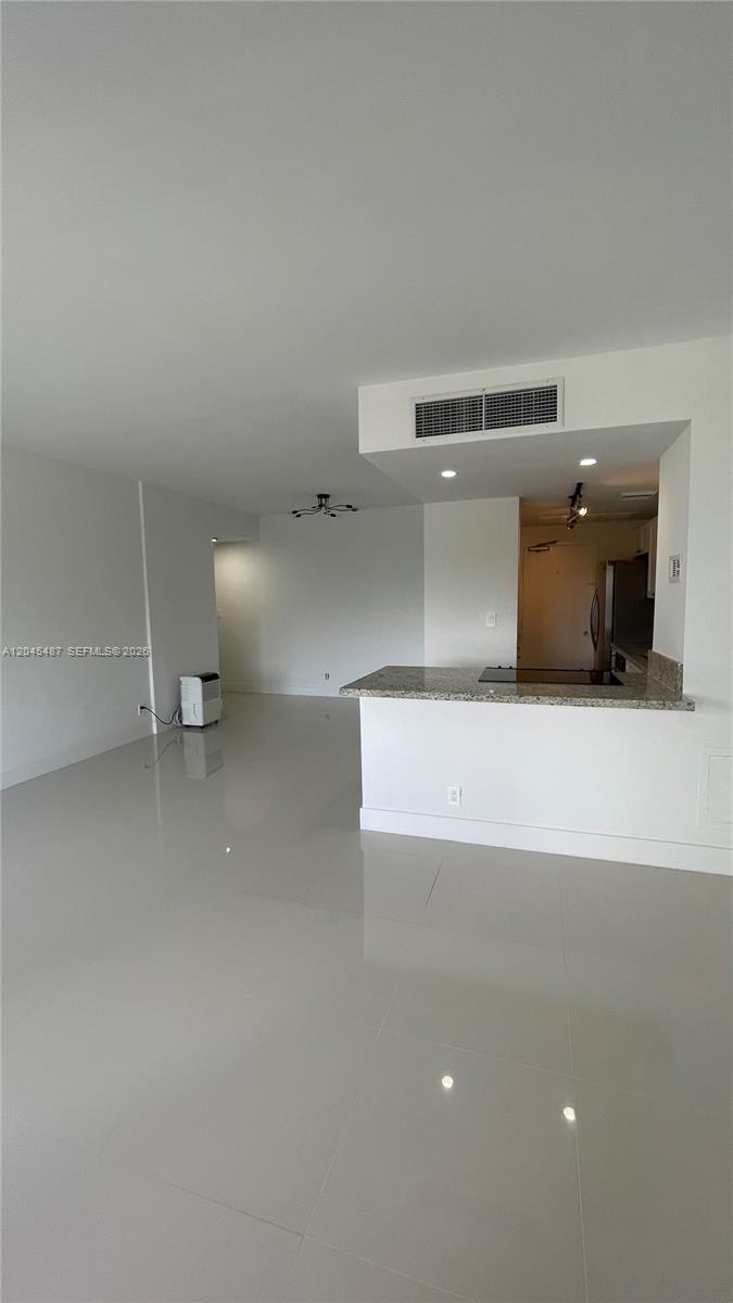 An open-concept living area features light-colored tile flooring and a kitchen with a granite countertop — 880 NE 69th St # 5L, Miami FL 33138, MIAMI, FL