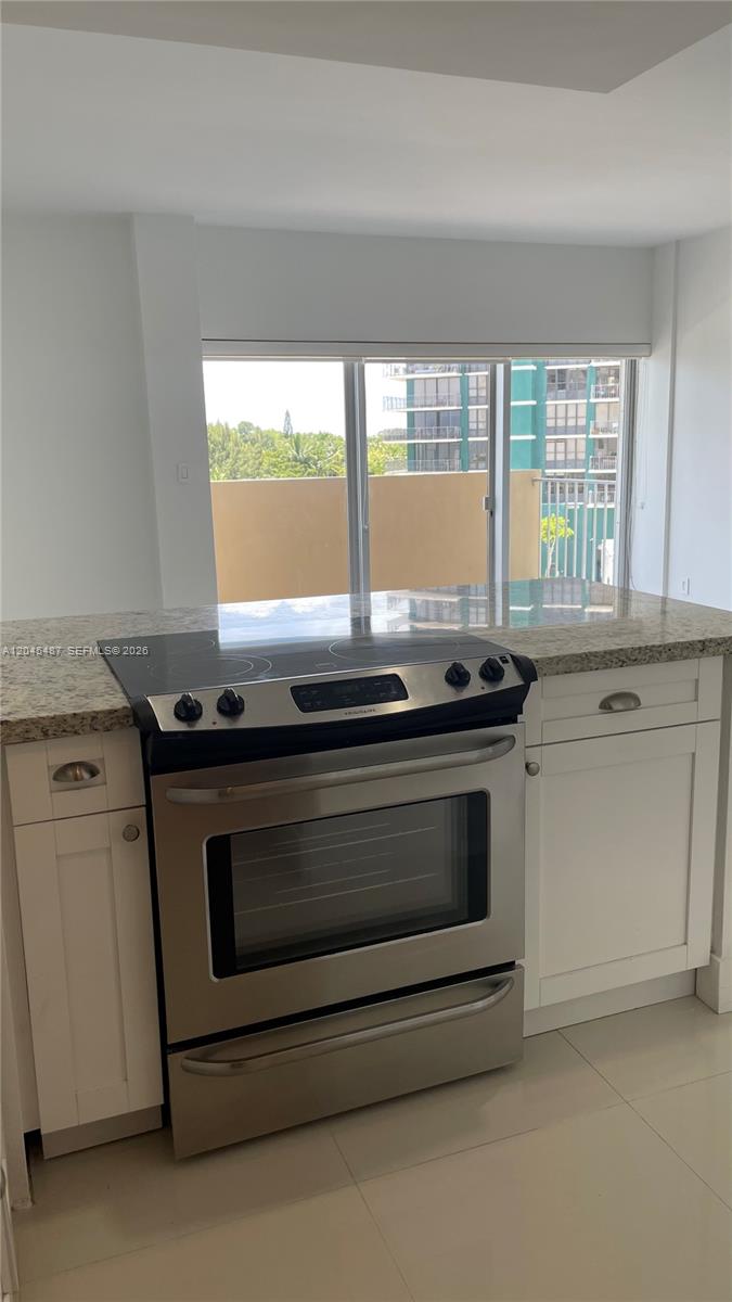 A stainless steel electric range is centered between white cabinets and a granite countertop — 880 NE 69th St # 5L, Miami FL 33138, MIAMI, FL