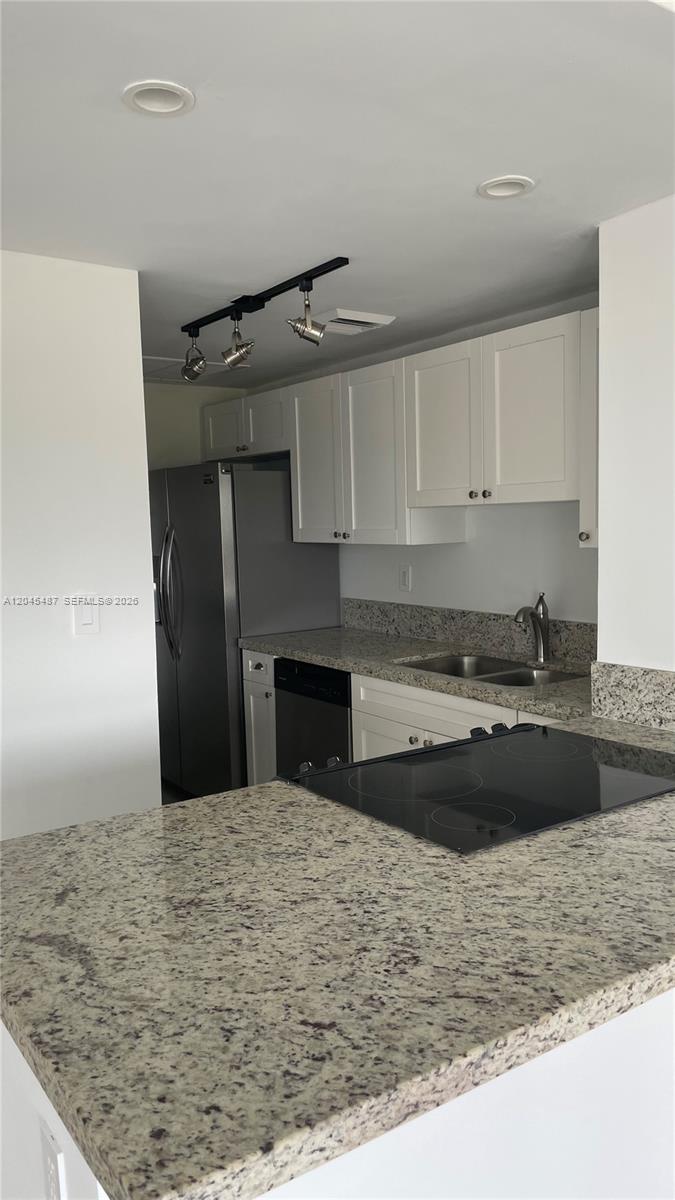 A kitchen features white cabinets, granite countertops, a stainless steel refrigerator, and a stovetop — 880 NE 69th St # 5L, Miami FL 33138, MIAMI, FL