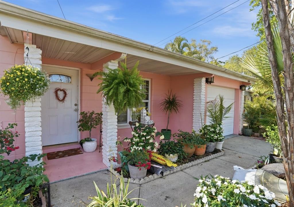 A pink house exterior features a white front door, white brick pillars, and potted plants — 6650 HIBISCUS AVENUE S, SOUTH PASADENA, FL