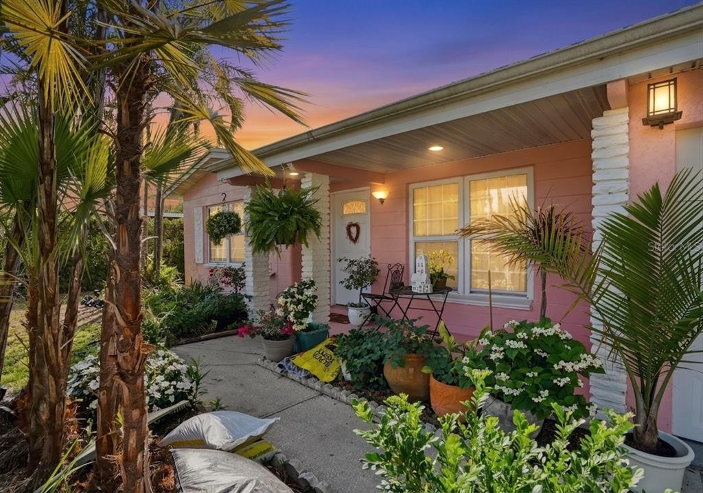 A pink house exterior features a front porch with potted plants and a white door — 6650 HIBISCUS AVENUE S, SOUTH PASADENA, FL