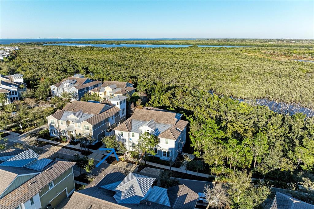 An aerial view shows multi-story residential buildings surrounded by dense trees near a coastal waterway — 339 SAPPHIRE LAKE DRIVE UNIT 201, BRADENTON, FL