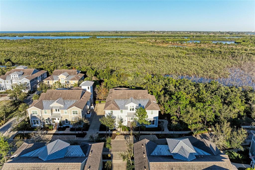 An aerial view shows several multi-story houses surrounded by dense trees and a distant waterway — 339 SAPPHIRE LAKE DRIVE UNIT 201, BRADENTON, FL