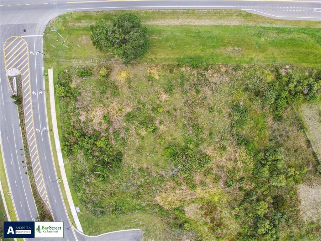 An aerial view shows a vacant, grassy lot bordered by a road and a sidewalk — 0 GALL BOULEVARD UNIT 2.59 Acres, ZEPHYRHILLS, FL