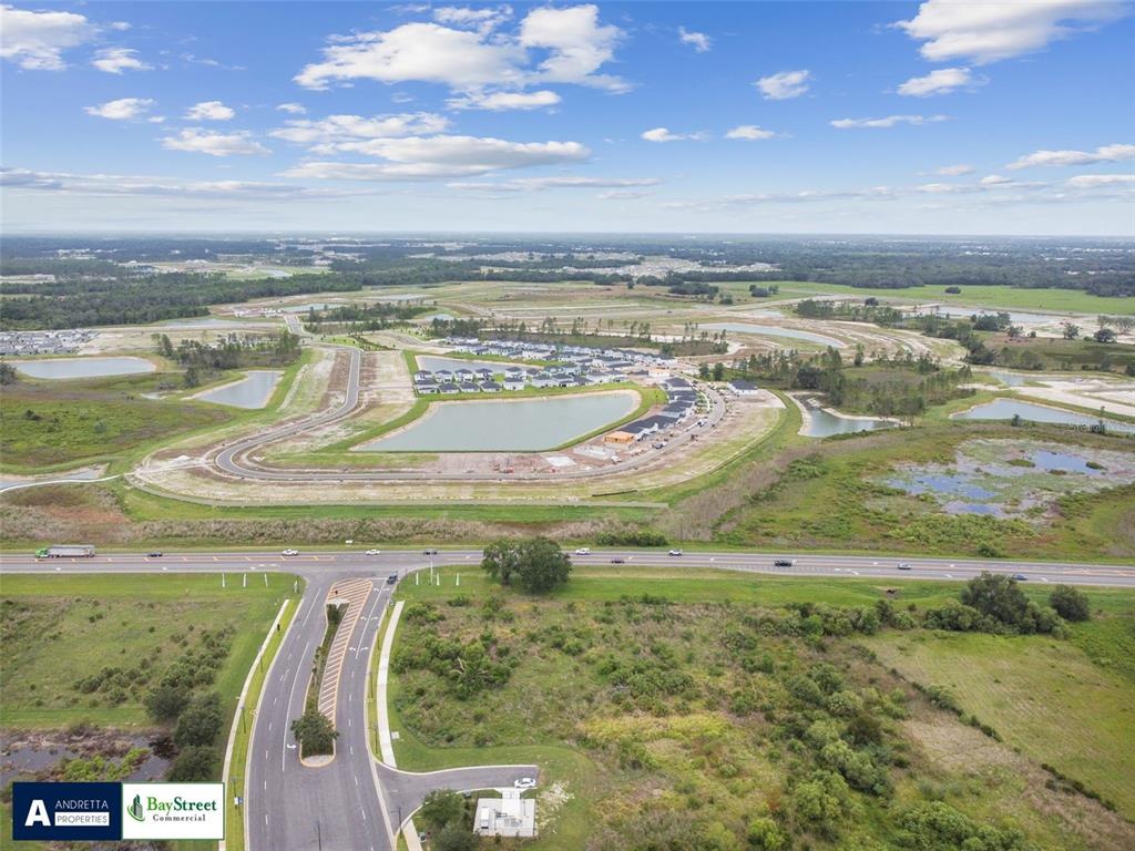 An aerial view shows a residential development under construction near a highway and ponds — 0 GALL BOULEVARD UNIT 2.59 Acres, ZEPHYRHILLS, FL