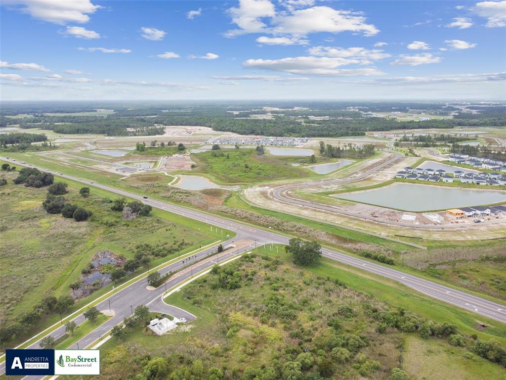 An aerial view shows a paved road intersection surrounded by undeveloped land and retention ponds — 0 GALL BOULEVARD UNIT 2.59 Acres, ZEPHYRHILLS, FL