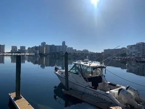 A white motorboat is docked in calm water with a city skyline in the background — 462 Golden Isles Dr # 202, Hallandale Beach FL 33009, HALLANDALE BEACH, FL