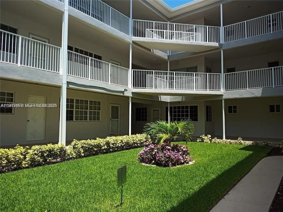 An exterior view of a multi-story apartment building with balconies overlooking a central courtyard — 462 Golden Isles Dr # 202, Hallandale Beach FL 33009, HALLANDALE BEACH, FL