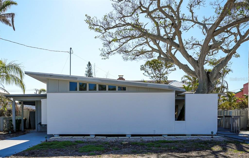 A modern, white, single-story house with a shed roof and clerestory windows under a tree — 132 HARRISON DRIVE, SARASOTA, FL