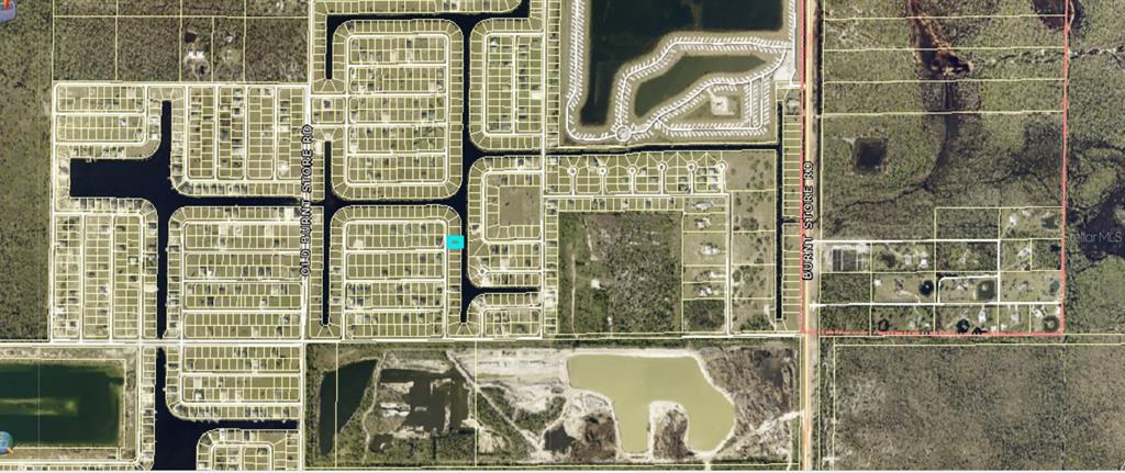 A wide, grassy vacant lot under a clear blue sky with distant trees and houses — 3833 NW 38TH AVENUE, CAPE CORAL, FL