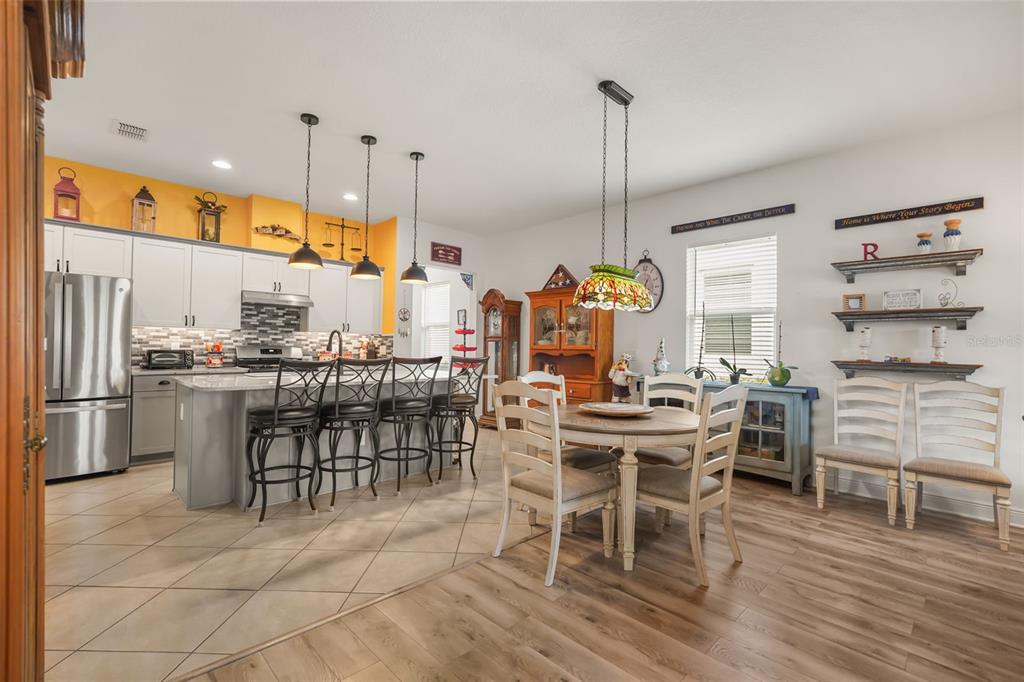 A kitchen with a yellow accent wall, island seating, and an adjacent dining area — 1667 KEY BAY TRAIL, KISSIMMEE, FL