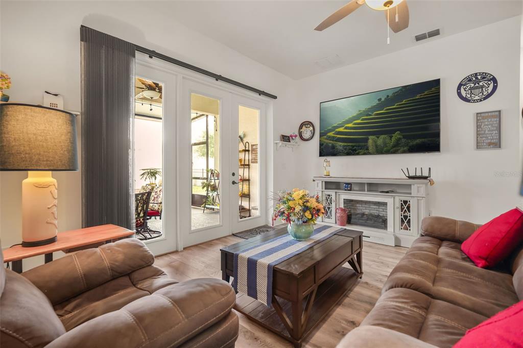 A living room features brown sofas, a coffee table, a fireplace console, and glass patio doors — 1667 KEY BAY TRAIL, KISSIMMEE, FL