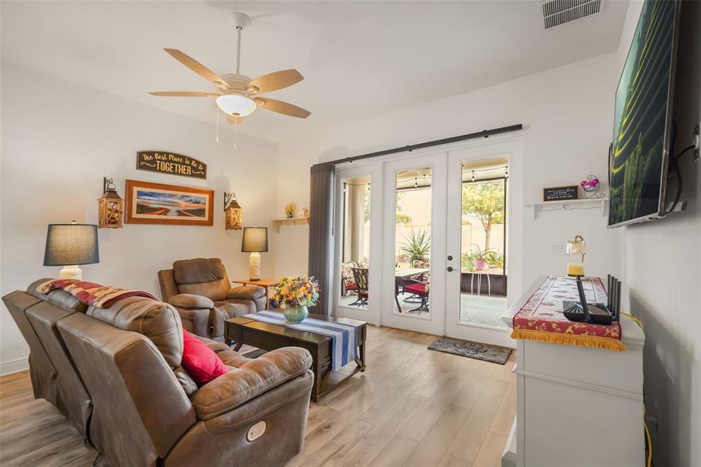 A living room with brown leather furniture, a ceiling fan, and glass doors to a patio — 1667 KEY BAY TRAIL, KISSIMMEE, FL