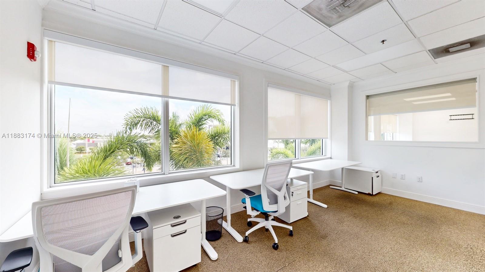An office space features white desks, mesh chairs, large windows with palm trees, and carpeting — 7950 NW 53rd St # 332, Doral FL 33166, DORAL, FL