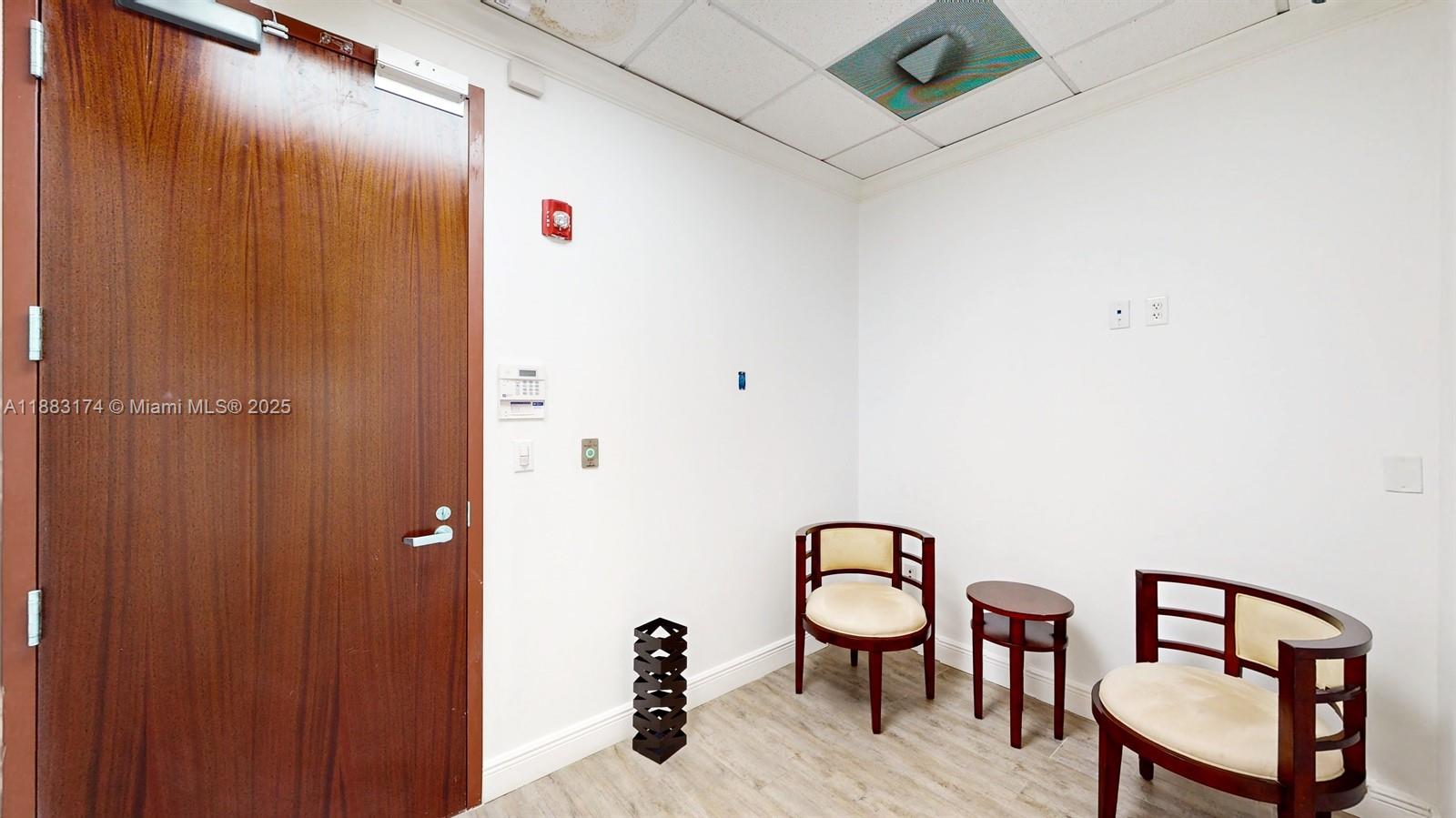 A small office room features a wood door, two chairs, a side table, and flooring — 7950 NW 53rd St # 332, Doral FL 33166, DORAL, FL