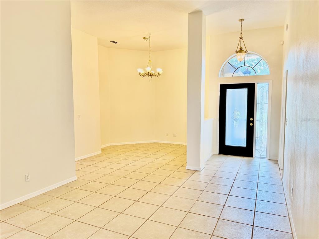 An entryway with tiled floors leads to a dining area featuring a chandelier — 1959 WOOD TRAIL STREET, TARPON SPRINGS, FL