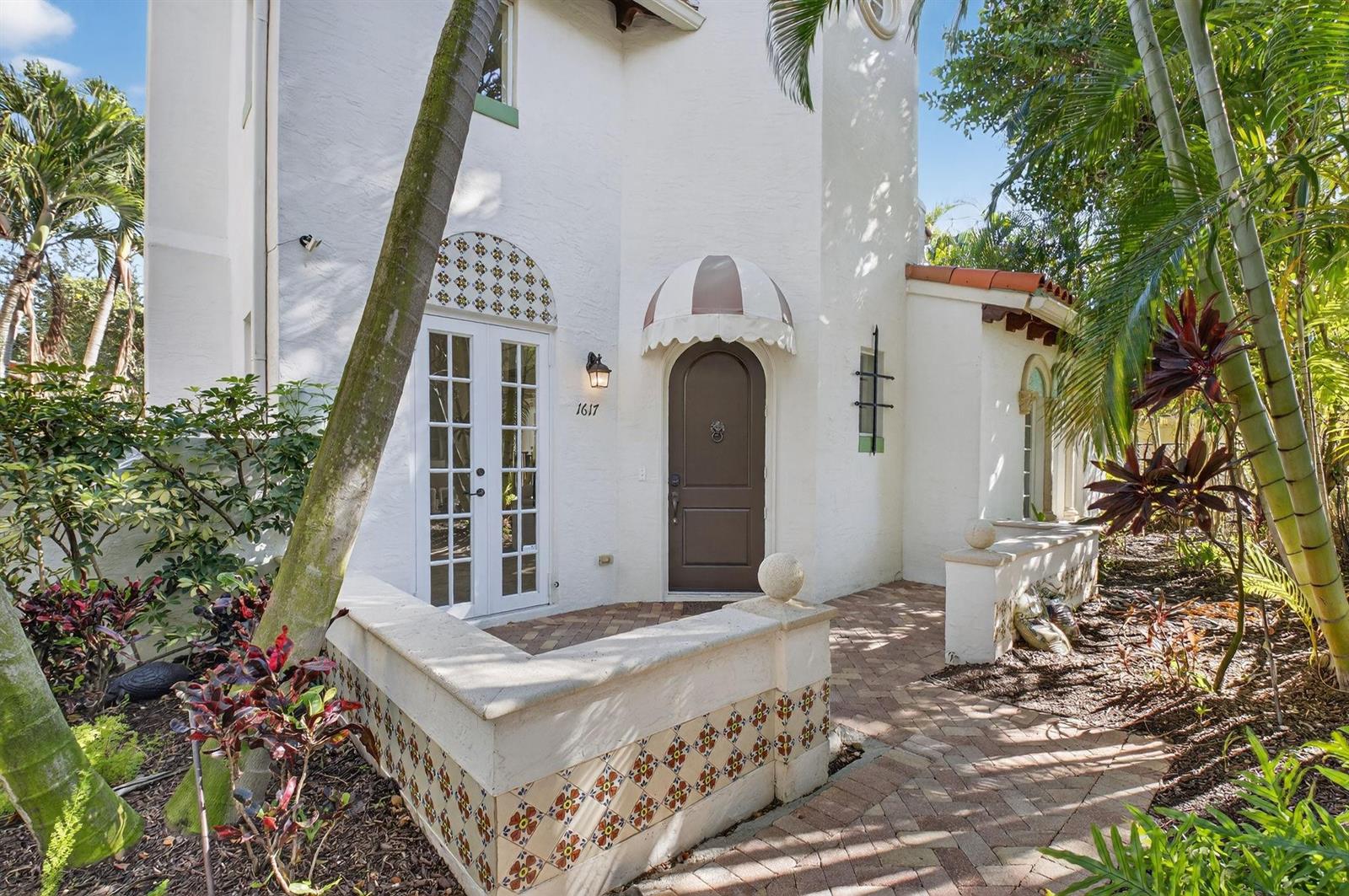 The exterior of a white stucco house features a brown arched door and French doors — 1617 Estuary Way, Delray Beach FL 33483, DELRAY BEACH, FL