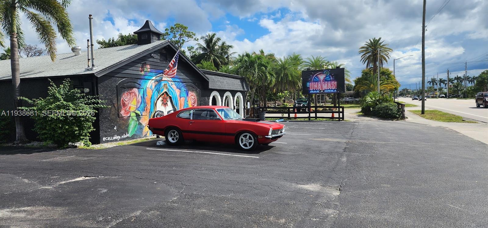 A red vintage car is parked in front of a building with a mural — 3801 N 10th Ave N, Palm Springs FL 33461, PALM SPRINGS, FL