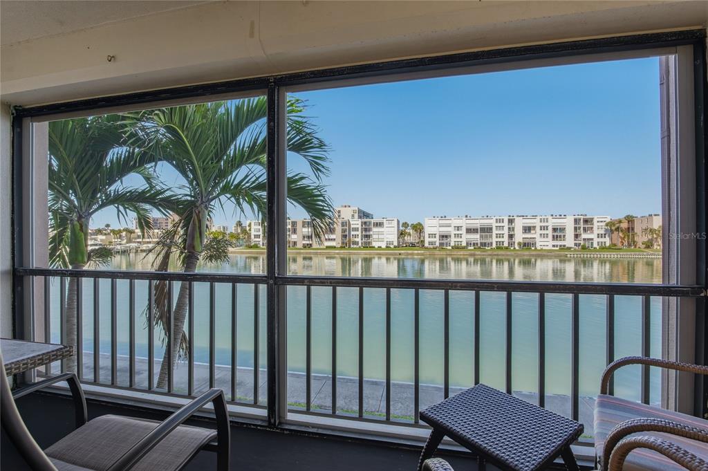 A screened-in balcony overlooks a calm body of water and a distant apartment complex — 7540 BAY ISLAND DRIVE S UNIT 251, SOUTH PASADENA, FL
