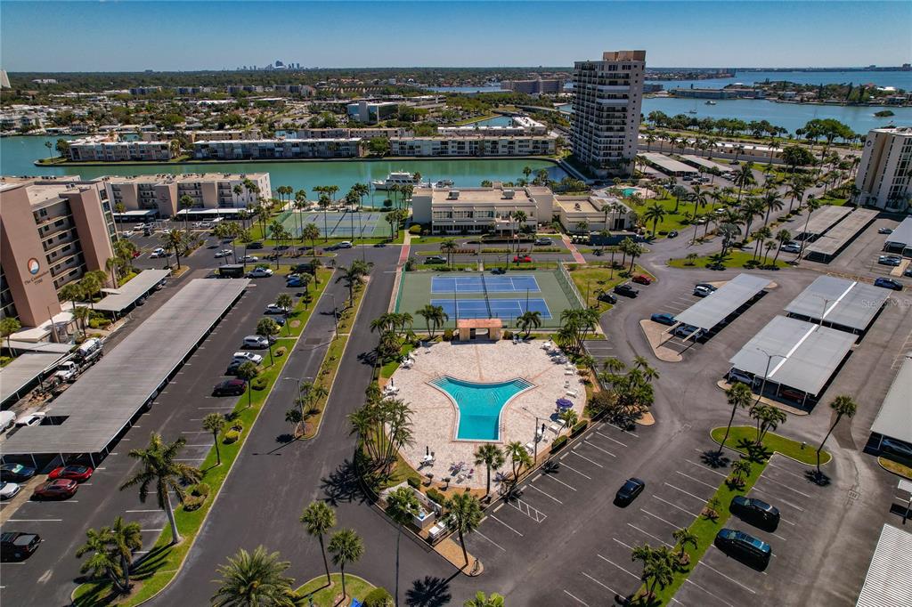An aerial view shows a swimming pool, tennis courts, parking lots, and surrounding apartment buildings — 7540 BAY ISLAND DRIVE S UNIT 251, SOUTH PASADENA, FL
