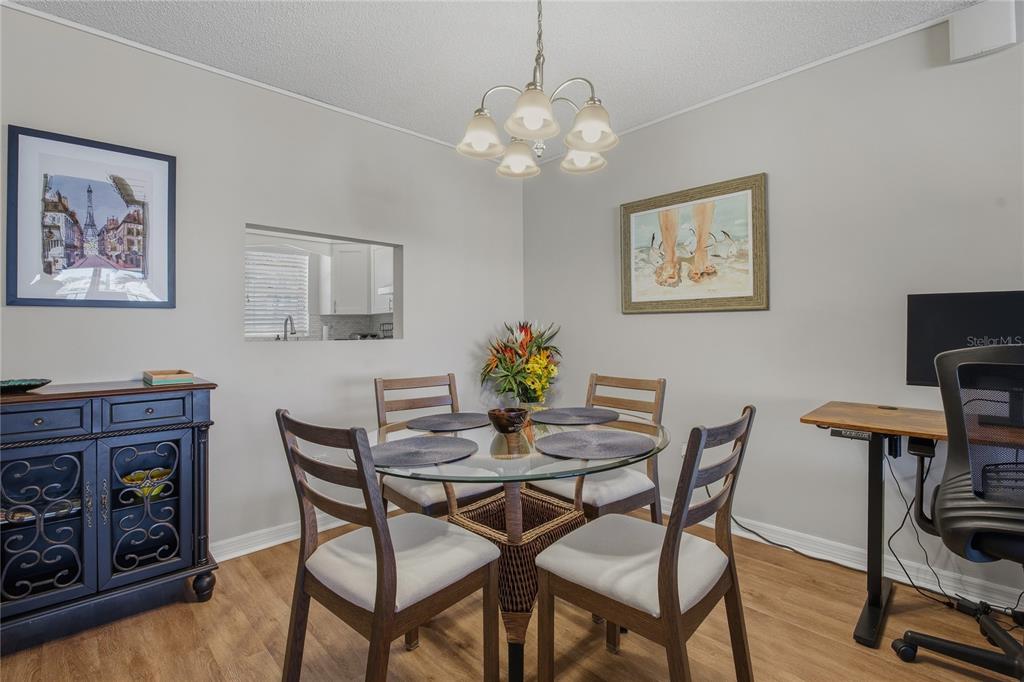 A dining room features a glass-topped table, four chairs, a chandelier, and a side cabinet — 7540 BAY ISLAND DRIVE S UNIT 251, SOUTH PASADENA, FL