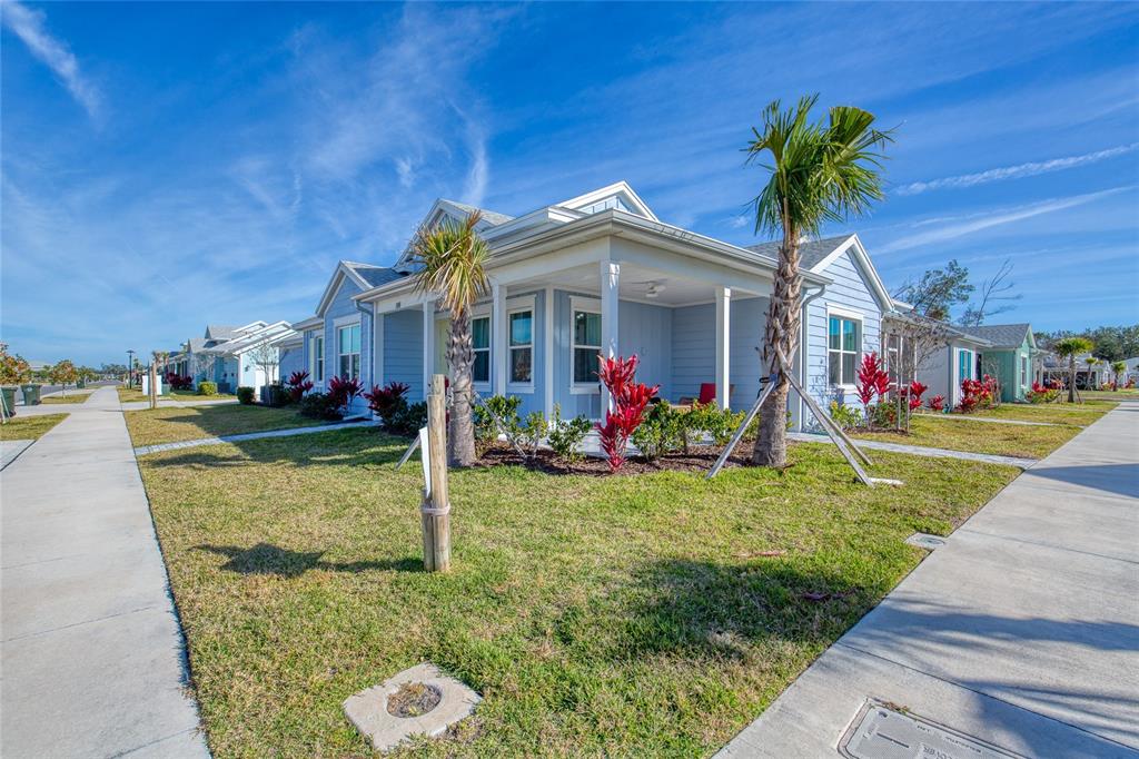 A light blue single-story house with a front porch and palm trees on a sunny day — 198 GYPSY PALACE LANE, DAYTONA BEACH, FL