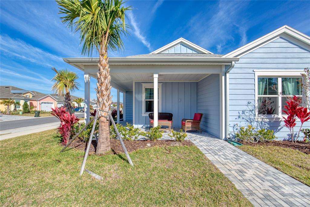 A light blue house features a covered front porch, a paver walkway, and palm trees — 198 GYPSY PALACE LANE, DAYTONA BEACH, FL